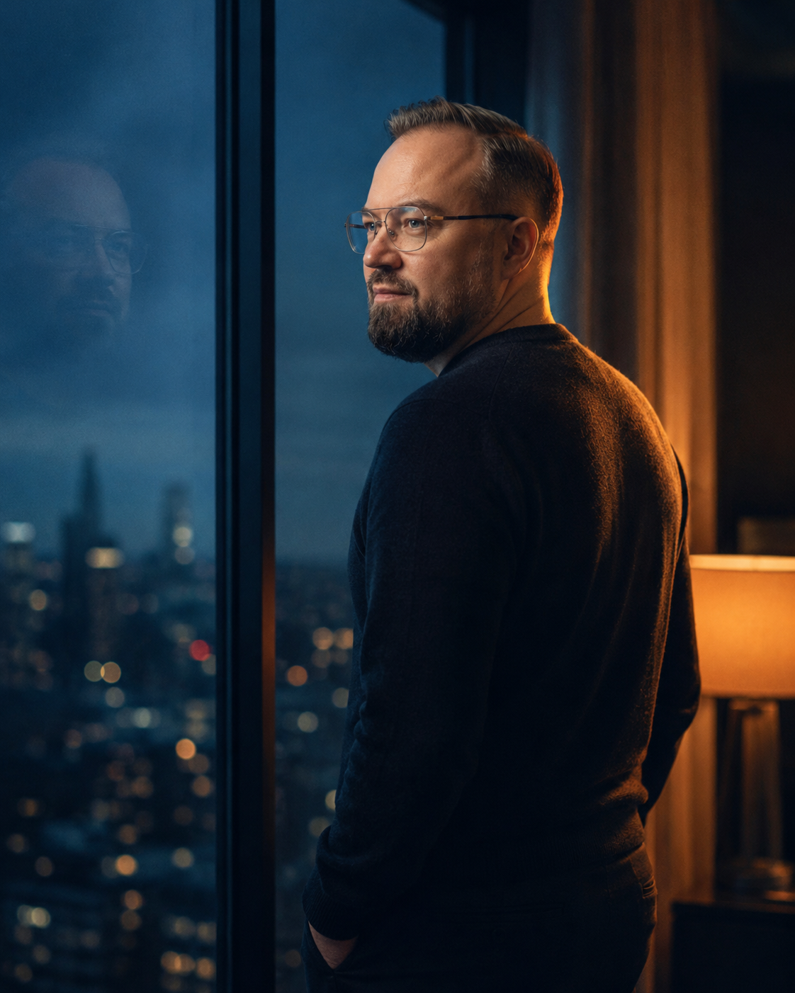 Kamil przy oknie, refleksja w szybie, miasto wieczorem